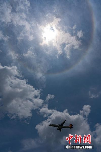 7月10日上午，一架飞机从出现日晕的空中飞过。当日，贵阳市上空出现日晕景观。据了解，日晕也叫圆虹，一种大气光学现象，是日光通过卷层云时，受到冰晶的折射或反射而形成的。中新社记者 贺俊怡 摄