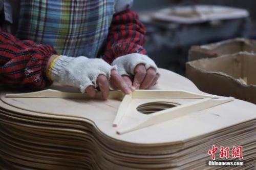 资料图为工人在制作吉他面板的内部。中新社记者 瞿宏伦 摄